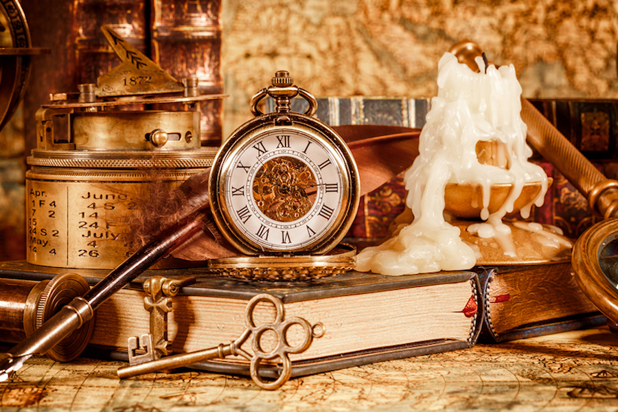 Vintage book, compass, telescope and a pocket watch lying on ancient world map in 1565.
